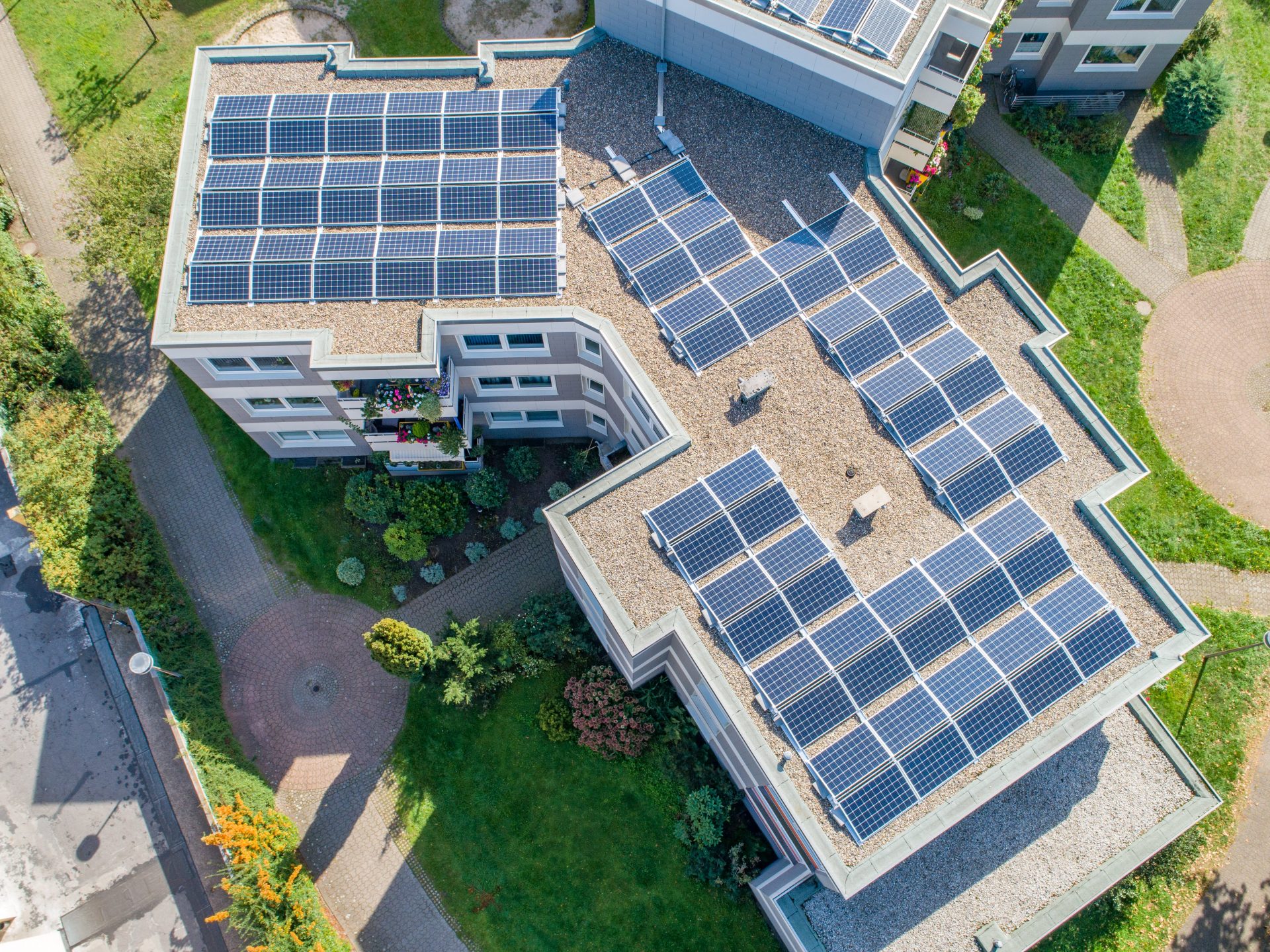 Solarpanele auf dem Dach eines Mehrfamilienhauses, aus der Luft aufgenommen.